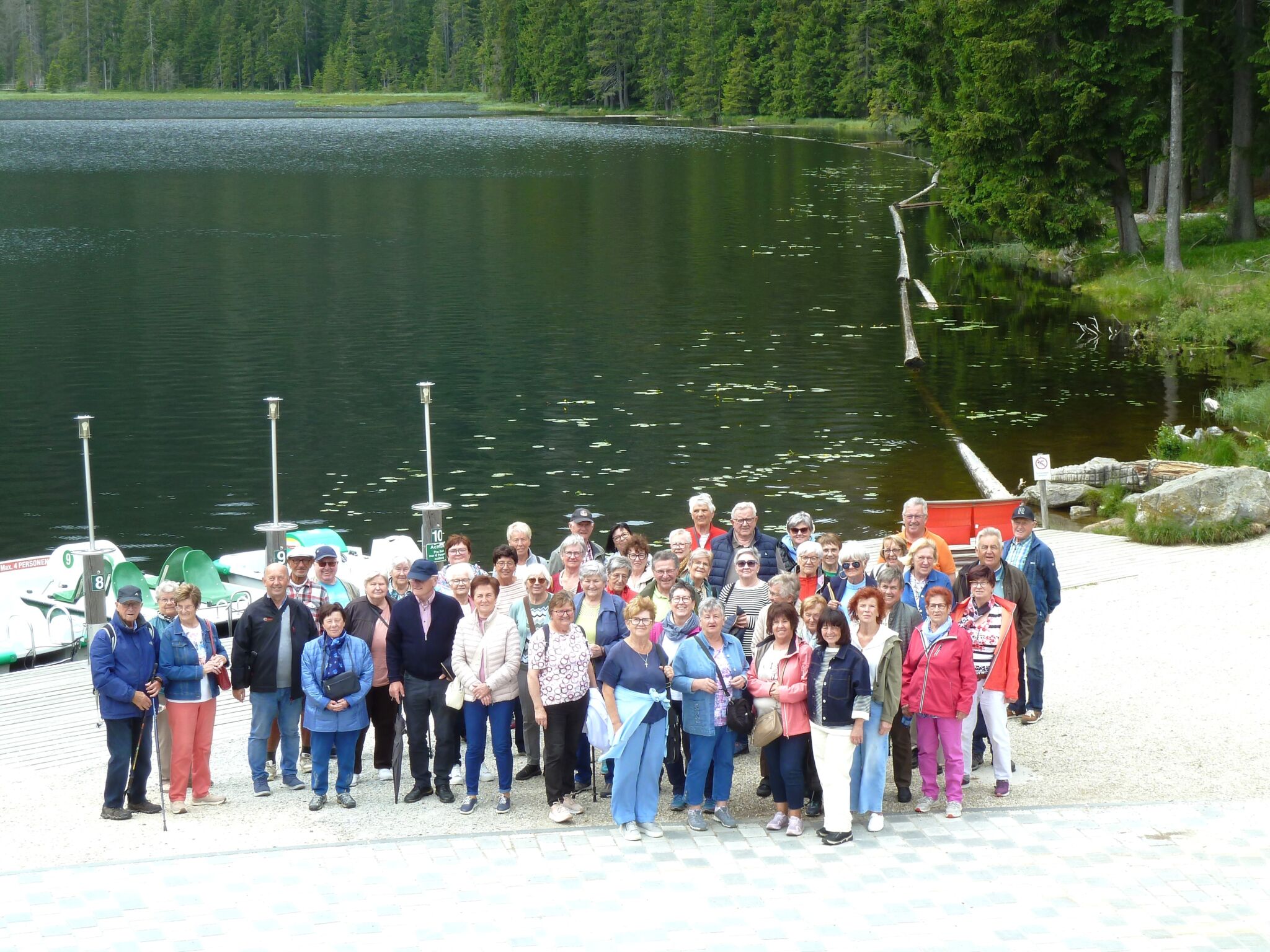 Die rund 50 Seniorinnen und Senioren stehen vor dem Großen Arbersee. Im Hintergrund erstreckt sich der See in satten Grüntönen umgeben vom bewaldeten Ufer.